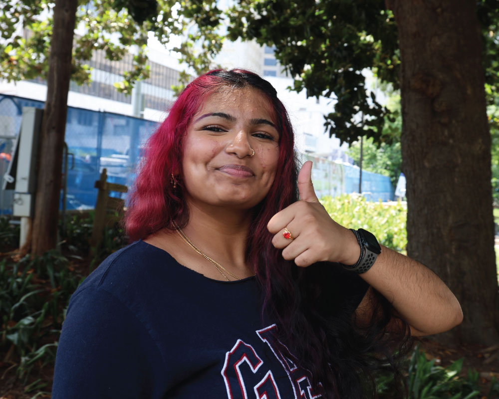 a smiling student holding up the good sign
