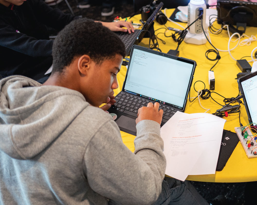 student referencing instructions on a paper while on the laptop